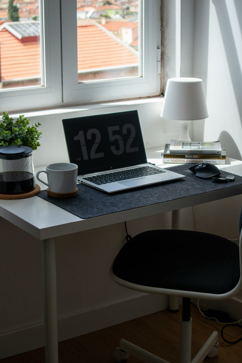 Escritorio de oficina en casa moderno con portátil, taza y planta.